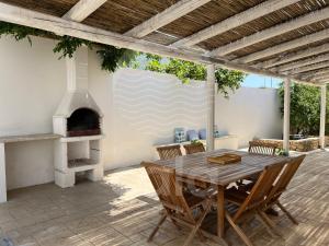 トッレ・ラピッロにあるVilla Teresa - giardino privatoの木製テーブルと屋外オーブン付きのパティオ