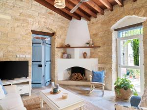 sala de estar con pared de piedra y chimenea en Villa Avgoustis, en Pachna