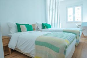 1 Schlafzimmer mit 2 Betten in Grün und Weiß in der Unterkunft NEW Estrela da Praceta Apt w/ 3 Suites & Oceanview in Carcavelos