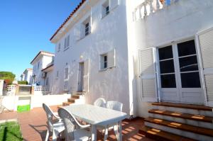 un patio con mesa y sillas junto a un edificio blanco en Casas La Vinya I, en L'Escala