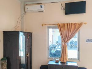 uma sala de estar com uma janela e uma ventoinha em New Era Family Homestay Binjai Mitra RedDoorz em Binjai