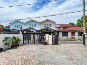 uma grande casa branca com um portão preto em New Era Family Homestay Binjai Mitra RedDoorz em Binjai