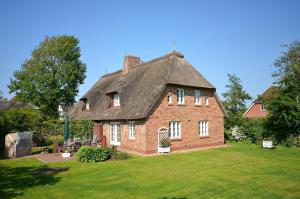 a large brick house with a thatched roof at Süderende- Süderhüs in Süderende