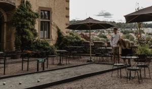 胡斯克瓦納的住宿－Hotel Slottsvillan，站在桌子和椅子附近的伞下的一个男人