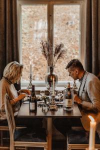 Dos personas sentadas en una mesa con botellas de vino en Hotel Slottsvillan en Huskvarna