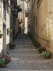 un callejón con escaleras y flores en un casco antiguo en Puteha - Arco Pronti, en SantʼAgata di Puglia