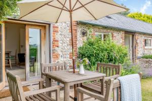 - une table et des chaises en bois avec un parasol sur la terrasse dans l'établissement Giddy Cottage, à East Dean