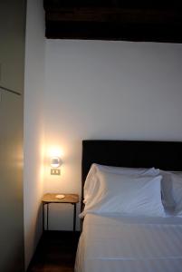 1 dormitorio con cama blanca y mesita de noche con lámpara en Vista Lago Apartment, en Bellagio