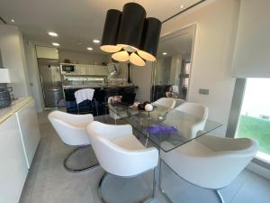 une salle à manger avec une table en verre et des chaises blanches dans l'établissement Villa Anita features privacy, sea views and private pool, à San Roque
