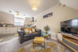 a living room with a couch and a large tv at The Coach House W in Wells next the Sea