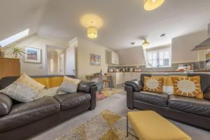 a living room with two leather couches and a kitchen at The Coach House W in Wells next the Sea