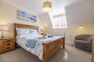 a bedroom with a large bed and a chair at The Coach House W in Wells next the Sea