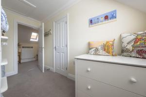 a white room with a dresser and a hallway at The Coach House W in Wells next the Sea +21 photos