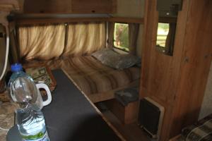 een kleine kamer met een bed en een fles water bij Caravan Yard in Valdemārpils