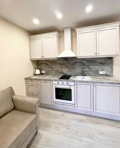 a kitchen with white cabinets and a sink and a couch at Namukas Kunigiškėse in Palanga