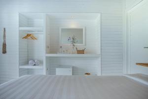 Habitación blanca con cama y espejo en Stardust Villas, en Nusa Lembongan