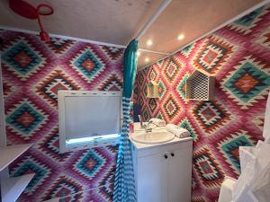 La salle de bains est pourvue d'un lavabo et d'un mur coloré. dans l'établissement Przyczepy Kempingowe OSK LOK by Q4Camp, à Jastarnia