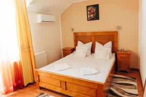 a bedroom with a bed with white sheets and pillows at Vila Carmen-camere de închiriat 3 stele in Baile Unu Mai
