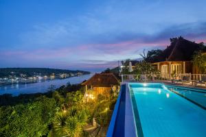 a swimming pool with a view of a river at night at Stardust Villas in Nusa Lembongan