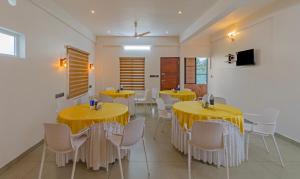 uma sala de jantar com mesas amarelas e cadeiras brancas em Treebo Trend Amigos Residency em Cochin