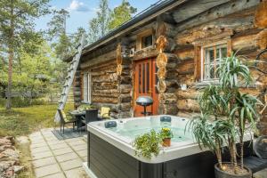 a hot tub in front of a log house at Kuukkeli Hirvas Suite in Saariselka
