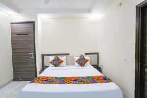 1 dormitorio con 1 cama blanca grande con almohadas coloridas en FabExpress Royal Orbit en Nueva Delhi