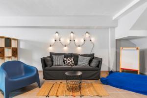 ein Wohnzimmer mit einem schwarzen Sofa und einem blauen Stuhl in der Unterkunft MEDANO4YOU Eternal Spring Holiday Home in El Médano