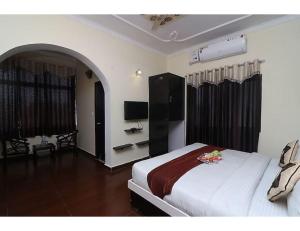 een slaapkamer met een bed en een televisie. bij Hotel Sparsh Ganga, Rishikesh in Rishīkesh