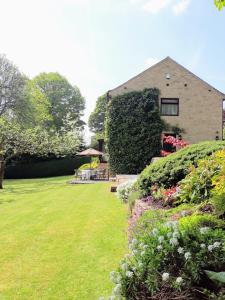a house with a green yard with flowers and bushes at Maywalk House B&B in Eyam
