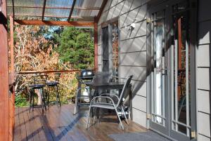a porch with a table and chairs and a grill at The Bower at Wildside Sanctuary in Bilpin