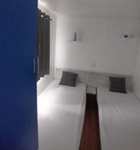 two beds in a room with white walls at Mobil home 6 pers. climatisé in Agde
