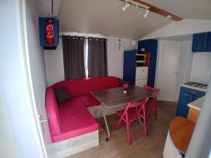 a living room with a red couch and a table at Mobil home 6 pers. climatisé in Agde