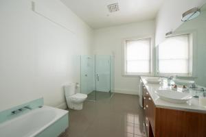 La salle de bains blanche est pourvue de 2 lavabos et de toilettes. dans l'établissement Roxburgh House Apartments, à Hobart