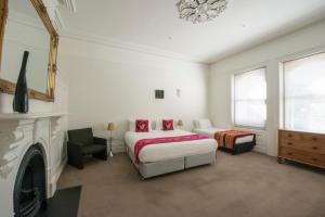 - une chambre avec un lit, une chaise et une cheminée dans l'établissement Roxburgh House Apartments, à Hobart