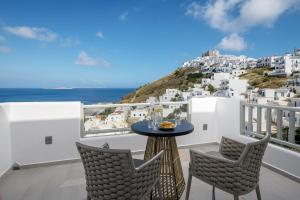 balcón con mesa, sillas y vistas al océano en Vivere Luxury Suites en Pera Gyalos