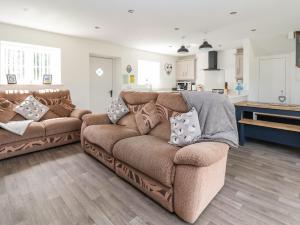 ein Wohnzimmer mit einer braunen Couch mit Kissen in der Unterkunft Cae Iocyn in Wrexham