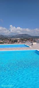 une grande piscine bleue avec une ville en arrière-plan dans l'établissement Apartamento con vista en L'Hospitalet del Infant, à Hospitalet de l'Infant