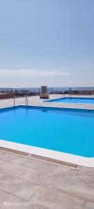 une grande piscine bleue avec l'océan en arrière-plan dans l'établissement Apartamento con vista en L'Hospitalet del Infant, à Hospitalet de l'Infant