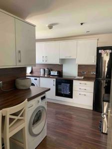 a kitchen with white cabinets and a washing machine in it at Cottage on the Loch in Arrochar