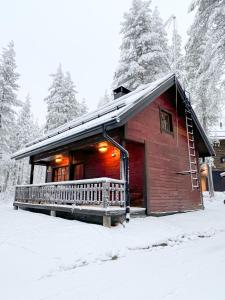een blokhut met een veranda in de sneeuw bij Black Work Levi Autti in Kittilä