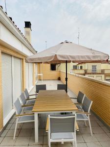 einen Holztisch mit Stühlen und einem Sonnenschirm auf dem Balkon in der Unterkunft Casa Palacio de los Sitios in Saragossa