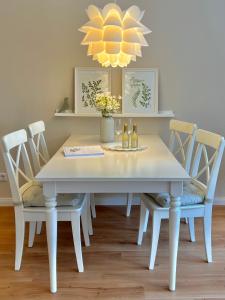 a white dining room table with chairs and a chandelier at "GartenTraum" - FeWo in Marienmünster - Ostwestfalen in Marienmünster