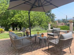 a patio with chairs and a table with an umbrella at Maison Tuscany Bed&Breakfast in Sinalunga