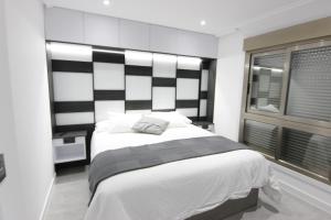 a bedroom with a bed with a black and white headboard at El Capricho de la ría II in O Grove