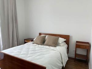 um quarto com uma cama grande com lençóis brancos e almofadas em Loft avec jardin chez l'habitant em Bagnolet