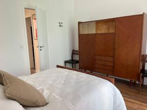 um quarto com uma grande cama branca e um armário de madeira em Loft avec jardin chez l'habitant em Bagnolet