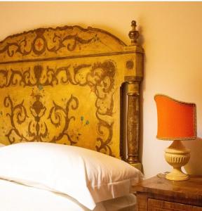 a bed with an ornate head board next to a table with a lamp at Umbrian cottage in Gubbio