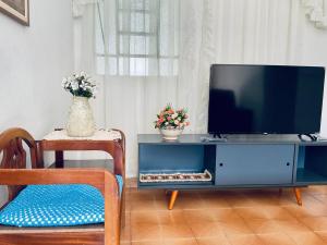 a living room with a tv on a blue entertainment center at Casinha da Vovó in São Lourenço