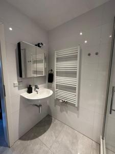 ein weißes Badezimmer mit Waschbecken und Spiegel in der Unterkunft Ferienvilla 10 Minuten vom Strand in Dirkshorn + 7 Fotos