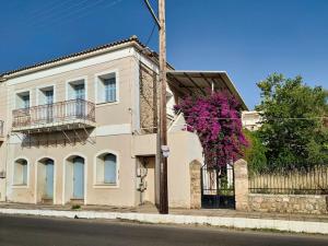 a house with a purple flowering tree in front of it at Στούντιο σε πέτρινο σπίτι, κοντά σε παραλία in Kyparissia